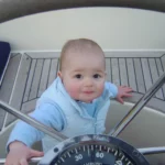 Zeilen met kleine kinderen. Rein achter het stuurwiel, 1 jaar en 2 maanden oud
