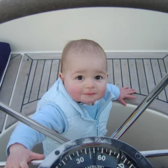 Zeilen met kleine kinderen. Rein achter het stuurwiel, 1 jaar en 2 maanden oud